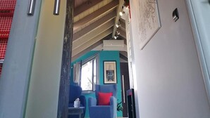 Eine Treppe mit Metallgeländern, die zu einem Raum mit einem blauen Stuhl und einem roten Kissen führt.