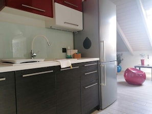 A modern kitchen with dark cabinetry, a stainless steel refrigerator, and a glass-top island.