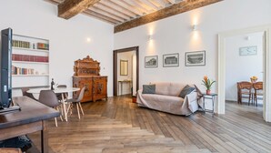 Un'ampia zona giorno con pavimento in legno, un divano, un tavolo da pranzo e una libreria.