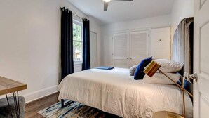 A bedroom with a bed, a desk, a ceiling fan, and a window with curtains. - Renovated 3BR LGD home near Magazine St. Walk to cafés, streetcar to FQ & Dome. (New Orleans)