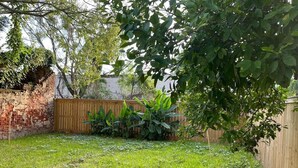 A backyard with a brick wall, wooden fence, and a grassy area with plants. - Renovated 3BR LGD home near Magazine St. Walk to cafés, streetcar to FQ & Dome. (New Orleans)