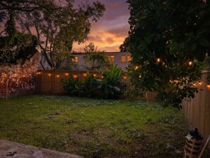A backyard with a brick wall, wooden fence, and string lights.
