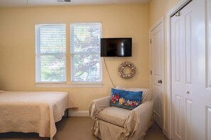 Quarto com duas camas, televisão, grinalda decorativa e uma porta.