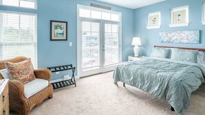 Une chambre à coucher comprenant un lit, une chaise, une table de chevet, une lampe et une fenêtre avec des stores.