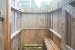 A wooden outdoor sauna with a bench and a faucet. - Mellow Yellow (Carolina Beach)