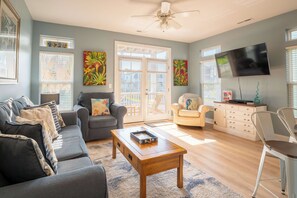 A living room with a grey sofa, a wooden coffee table, a television, and artwork on the walls.
