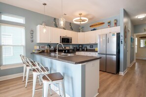 A modern kitchen with white cabinets, stainless steel appliances, and a central island with bar stools.