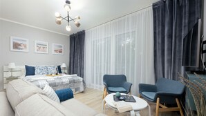 Una sala de estar moderna con un sofá, dos sillones, una mesita y un televisor.