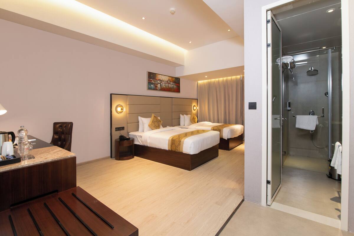 A hotel room with a bed, bedside table, and a shower area.