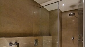 Casa de banho moderna com chuveiro em cabine de vidro, toucador com lavatório e espelho, e sanita.