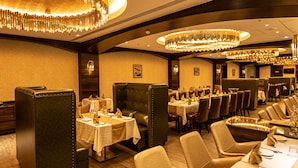 Um restaurante com assentos estofados, mesas redondas e lustres elegantes.