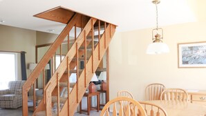 Un comedor con una escalera de madera, una mesa con sillas y una lámpara colgante.