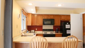 Una cocina con armarios de madera, microondas, estufa y refrigerador.