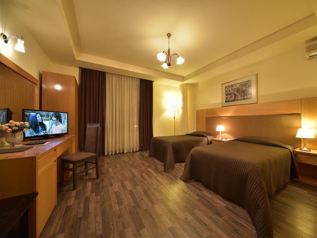 Hotellihuone, jossa on televisio, kaksi sänkyä, työpöytä ja tuoli.