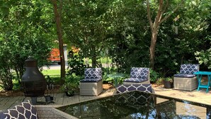 A patio area with wicker furniture, a small pool, and a barbecue grill.