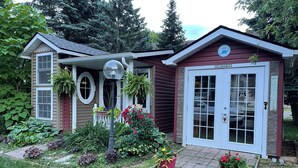 A small house with a garage, a porch with a lamp, and various plants.