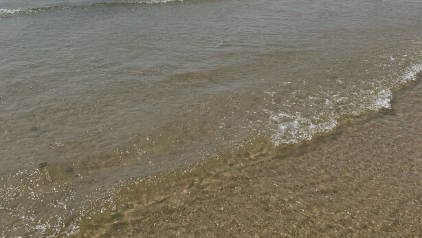 A beach with clear water and a distant shoreline.