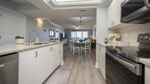 Een moderne keuken met witte kasten, een roestvrijstalen oven en een eethoek met een tafel en stoelen.