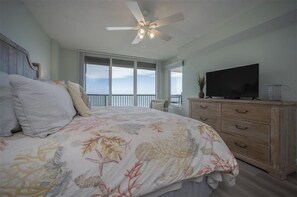 A bedroom with a bed, a ceiling fan, a TV, a dresser, and a balcony with a view. - 7402 Towers 8 and 9 - 2/2 Oceanfront Beauty on Traffic Free Beach - Ponce Inlet (Ponce Inlet)