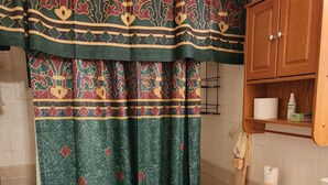 A bathroom with a toilet, a sink, a cabinet with toiletries, and a shower curtain with a decorative pattern. - Just Like Home (Memphis)