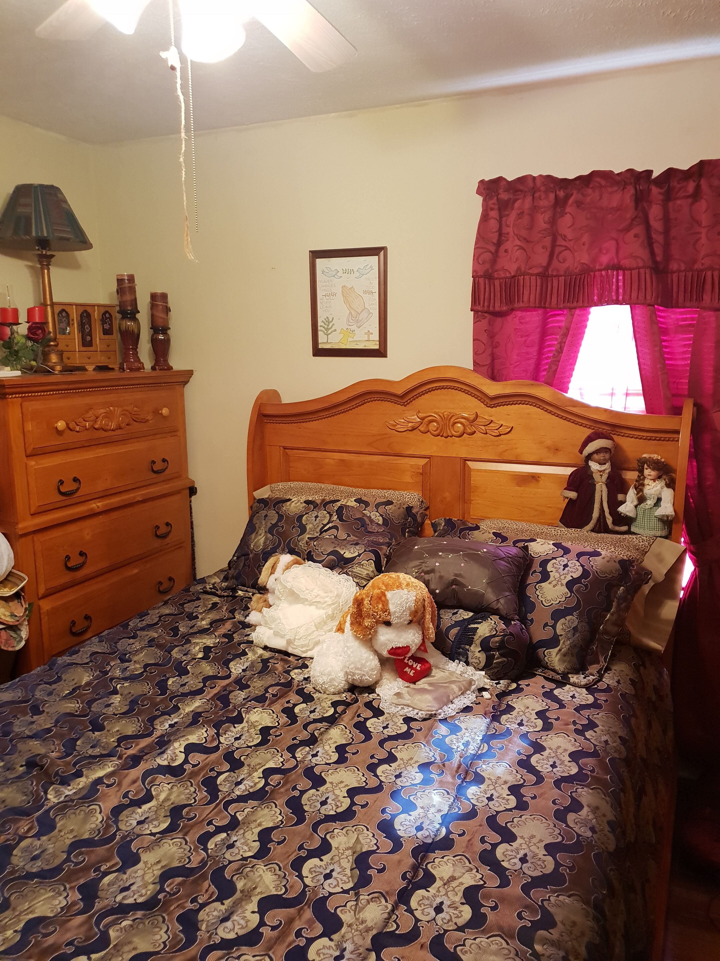 Une chambre à coucher avec un lit, une commode, une lampe et une fenêtre avec des rideaux.