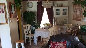 Una sala de estar con un sofá de cuero oscuro, una silla de madera, una mesa de comedor con mantel blanco y una araña.