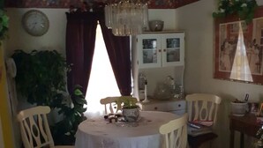 Un comedor con una mesa redonda, sillas, una lámpara de araña y un aparador con puertas de cristal.