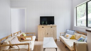 Ein Zimmer mit zwei Rattan-Sofas, einem Holztisch und einem Fernseher auf einem Schrank.