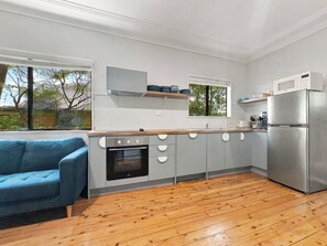 A modern kitchen with grey cabinets, a built-in oven, a microwave, and a stainless steel refrigerator. - Pearl Beach Semi - 2 min to sand & sea – Wattle (Pearl Beach)