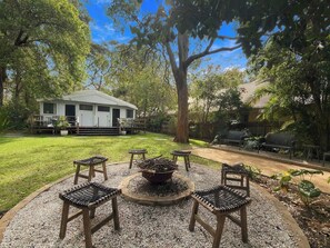 A backyard with a white house, a circular seating area with chairs, and a large tree. - Pearl Beach Semi - 2 min to sand & sea – Wattle (Pearl Beach)