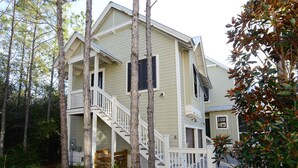 A two-story house with a front porch, a staircase leading to the second floor, and a small deck area. - WaterColor "Yum" |1 BR | Sleeps 4| Camp District |2 Bikes (Santa Rosa Beach)