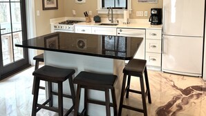 A modern kitchen with a central island, white cabinetry, and a refrigerator. - WaterColor "Yum" |1 BR | Sleeps 4| Camp District |2 Bikes (Santa Rosa Beach)