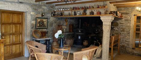 A rustic interior with wicker furniture, a stone fireplace, and wooden beams.