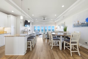 A spacious kitchen with a central island, dining area with chairs, and a view of the ocean.