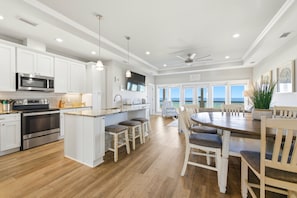 A spacious kitchen with white cabinets, a large island, and a dining area with a table and chairs.