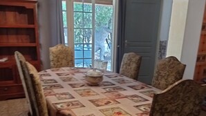 Une salle à manger avec une table recouverte d’une nappe à motifs, entourée de quatre chaises rembourrées.