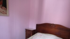 Ein hölzernes Bett mit floralem Bettbezug in einem Zimmer mit rosafarbenen Wänden.