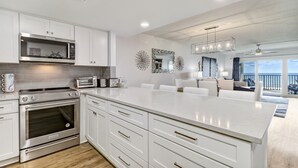 Une cuisine moderne avec des meubles blancs, des appareils en acier inoxydable et un grand îlot central.