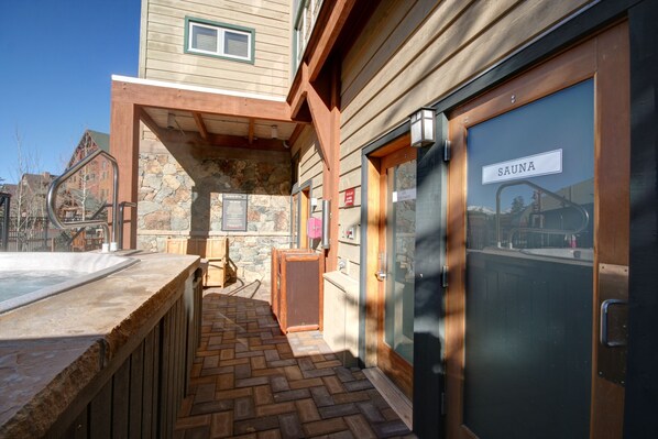 A spa area with a stone wall, wooden deck, and a sauna sign. - Steps to Gondola/Heart of River Run/Hot Tub (Keystone)