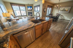 A kitchen with granite countertops, stainless steel appliances, wooden cabinets, and a dining area with a table and chairs.