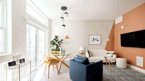 Een moderne woonkamer met een bank, een salontafel en een aan de muur bevestigde televisie.