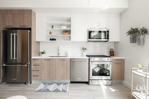 Una cocina moderna con electrodomésticos de acero inoxidable, armarios blancos y encimera de mármol.