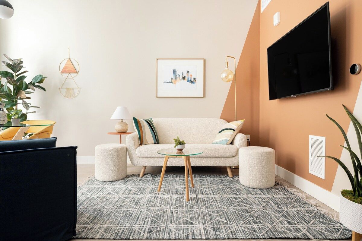 Un salon comprenant un canapé, une table basse, un téléviseur fixé au mur et un tableau encadré.