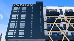 Een modern gebouw met de naam 'ESPADIN' op de gevel, met een geometrisch ontwerp, balkons en grote ramen.