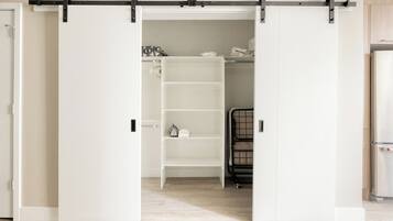 A room with a sliding closet door, a white shelving unit, and a black metal rack.