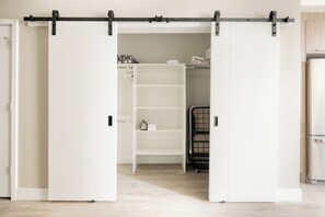 A room with a sliding closet door, a white shelving unit, and a black metal rack. - Colorful Western Vibe | Pet-Friendly | Zuni Lofts (Denver)