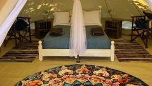 Une tente équipée d’un lit, d’un auvent suspendu et d’un tapis à motifs.