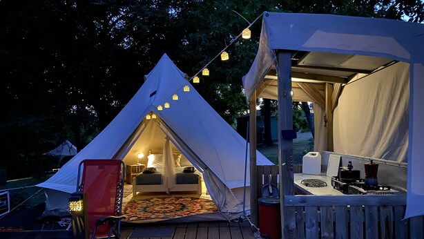 Une tente avec un lit, une petite table et une chaise sur une terrasse en bois.