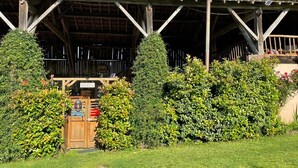 Un bâtiment rustique en bois, doté d’une entrée couverte, d’une enseigne et d’un petit espace extérieur aménagé avec des sièges.