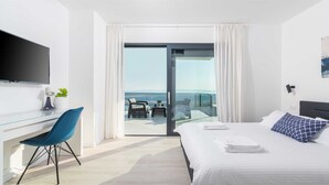 A modern hotel room with a bed, a desk, a chair, a TV, and a balcony with a view.